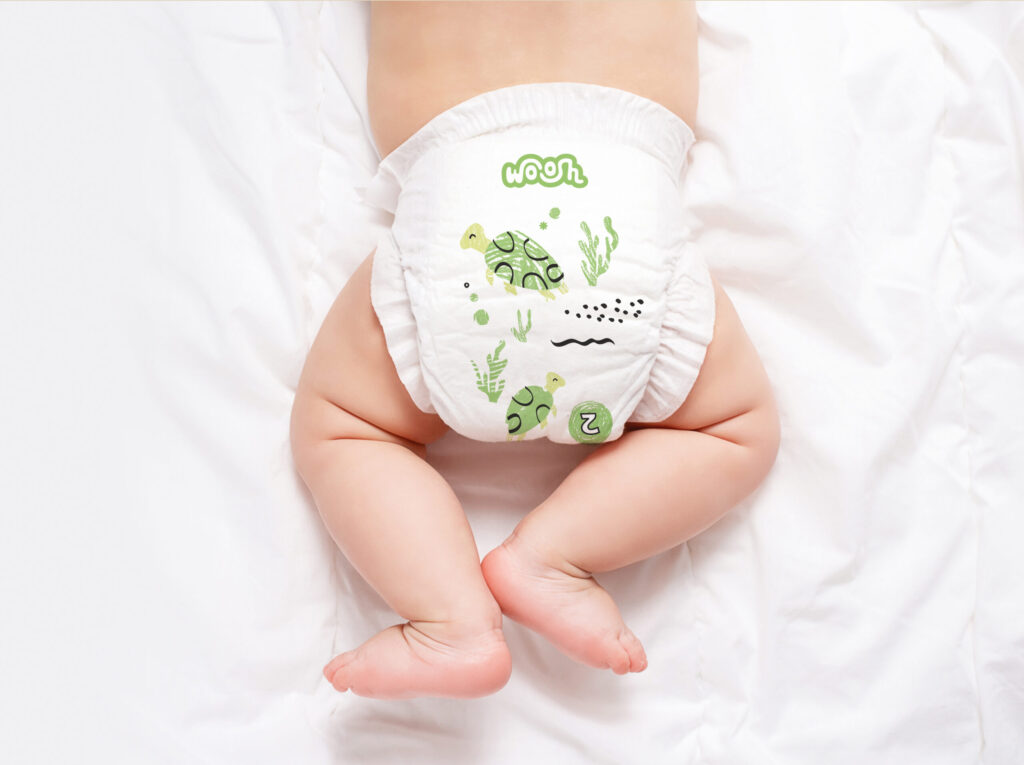 Cute caucasian infant baby in white nappy on light grey blanket. Top view. Banner format. Copy space. Diaper change and care of baby's skin.
